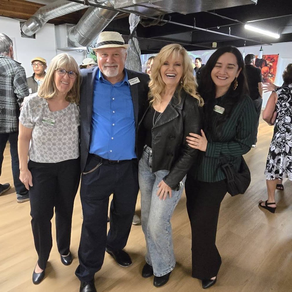 A group of four smiles for the camera at a networking mixer.