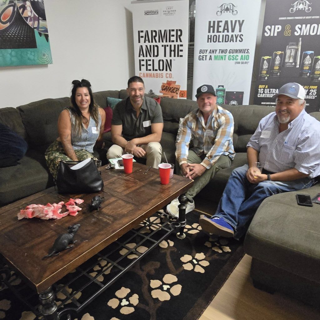 A group sits on couches near a coffee table at a networking event.