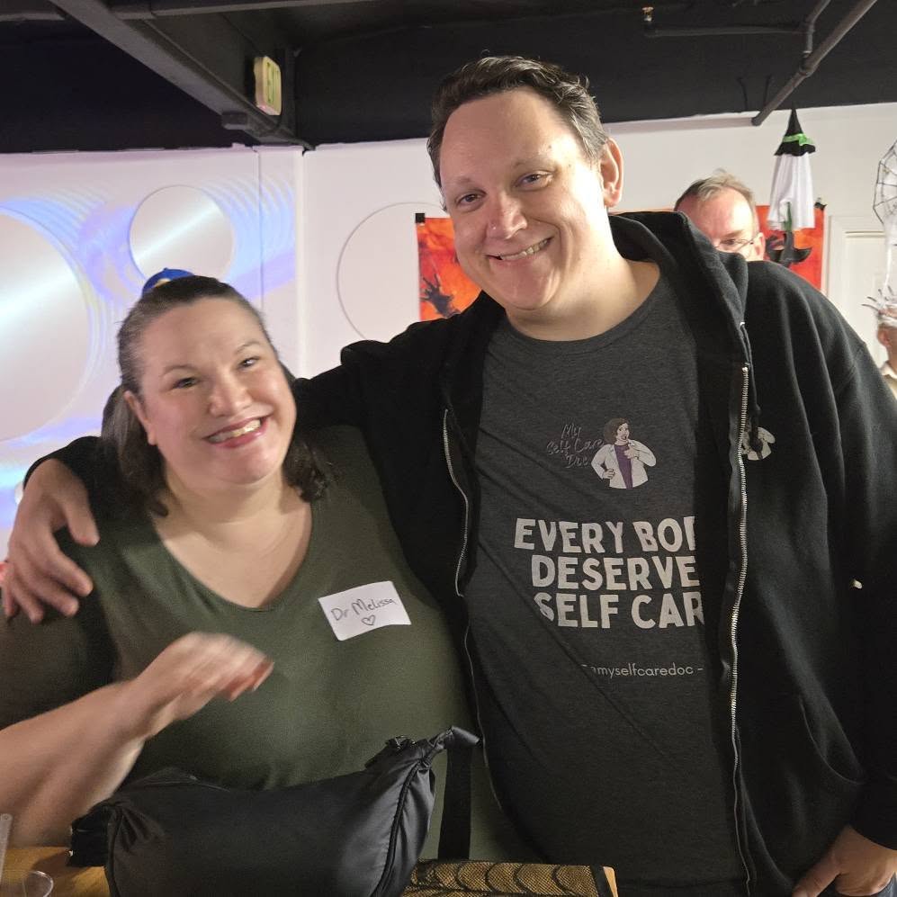 A woman and man smile at a networking event.