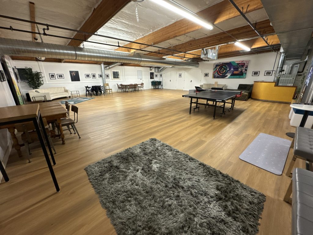 The Upstairs main event space, full of movable furnishings including a bar, rugs, ping pong table and other seating.